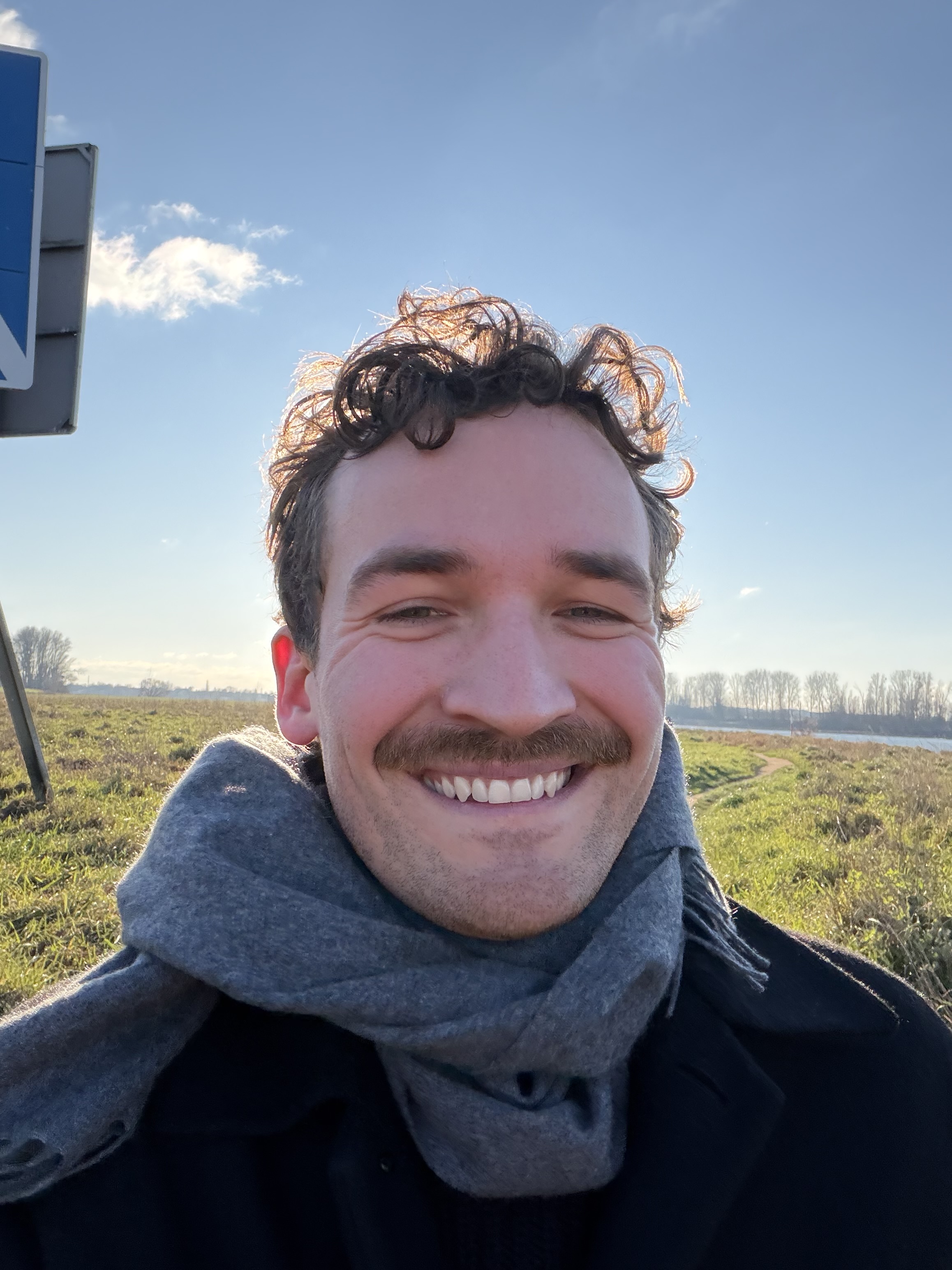 Julian Simon lächelt draußen am Rhein bei Köln